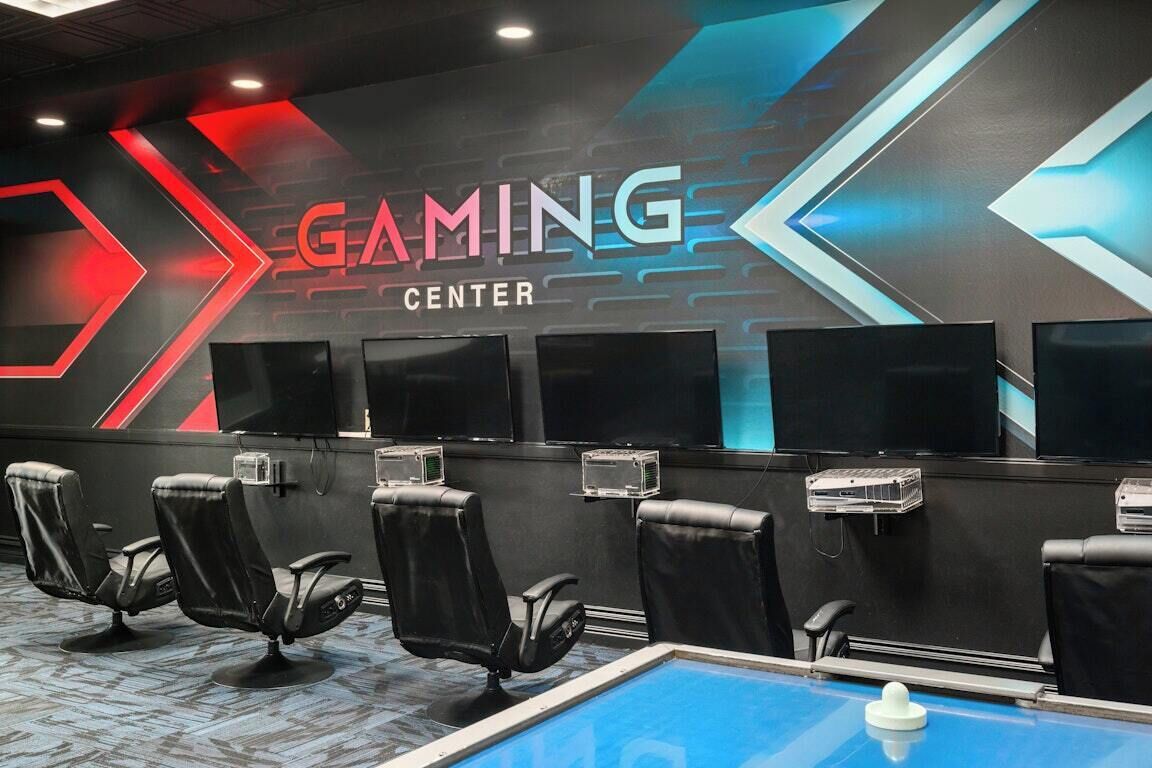 Un centro giochi con diverse postazioni, sedie e schermi di grandi dimensioni.