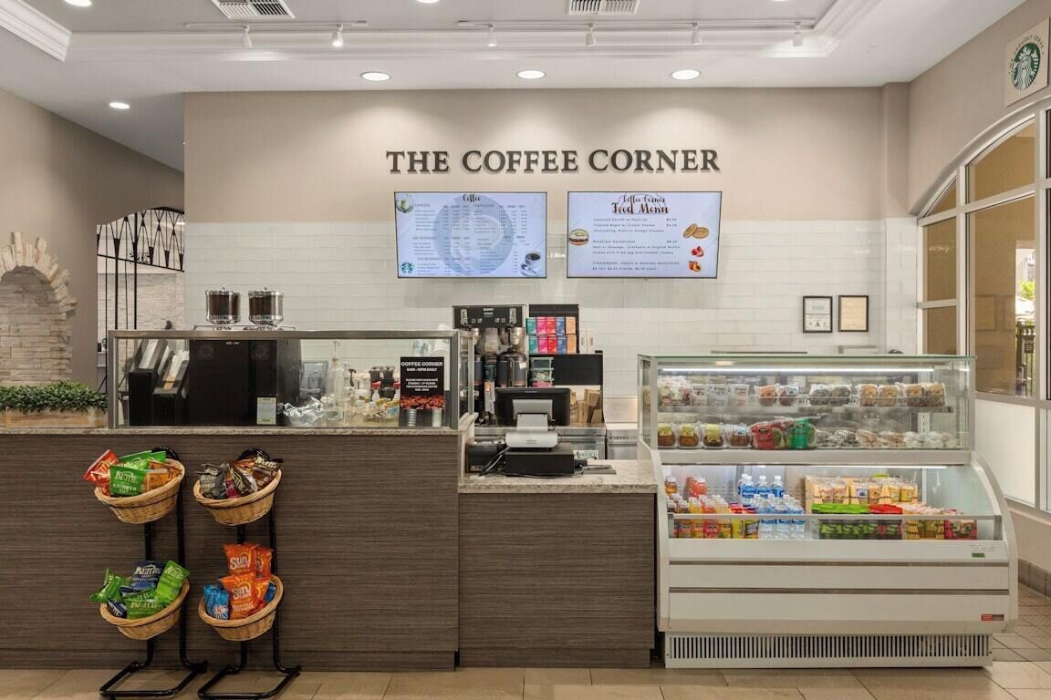 A coffee shop with a counter, menu boards, and a display case with snacks.