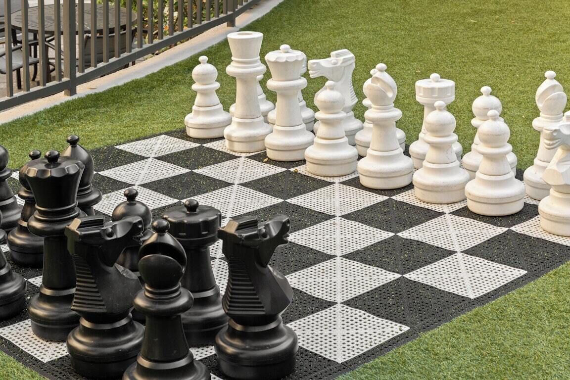 A chessboard with chess pieces on a grassy area.