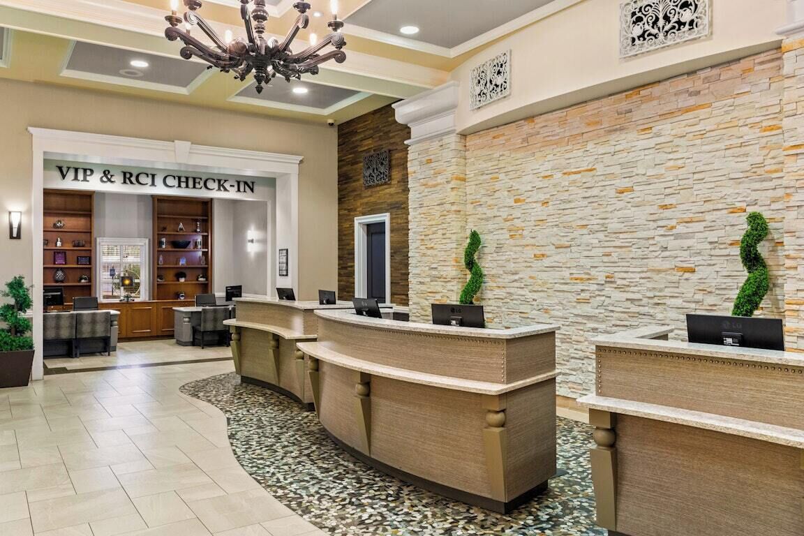 A reception area with a check-in desk, a chandelier, and a stone wall.