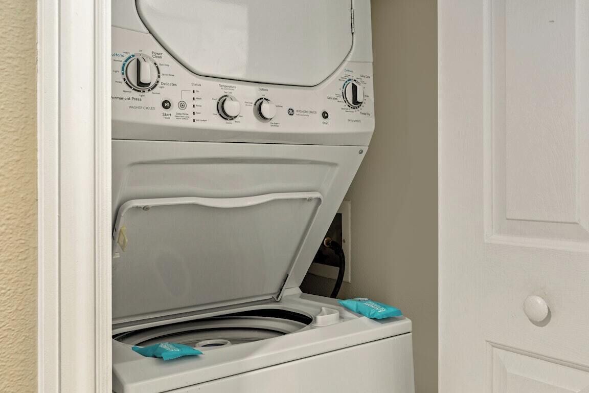 Un lave-linge à chargement frontal, doté d’un panneau de commande, d’une porte et d’une poignée fixée au mur.