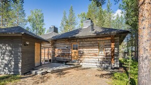 A rustic log cabin with a wooden door, a small porch, and a chimney.