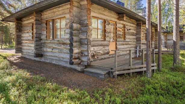 A log cabin with a wooden deck and large windows.
