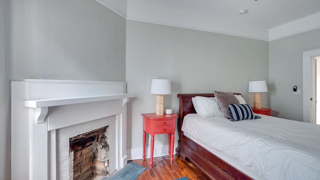 Une chambre à coucher avec une cheminée, un lit avec des oreillers et deux tables de chevet avec des lampes.