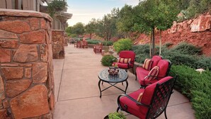 Un patio al aire libre con paredes de piedra, sillas rojas acolchadas y una mesa redonda.