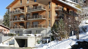 A multi-story wooden building with balconies, a garage, and a snow-covered landscape. - Apartment Raber by Interhome (Churwalden)