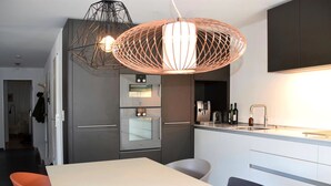 A modern kitchen with a large island, stainless steel appliances, and pendant lighting. - Apartment Raber by Interhome (Churwalden)