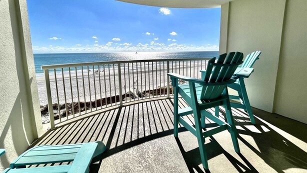 A balcony with a view of the beach and ocean.