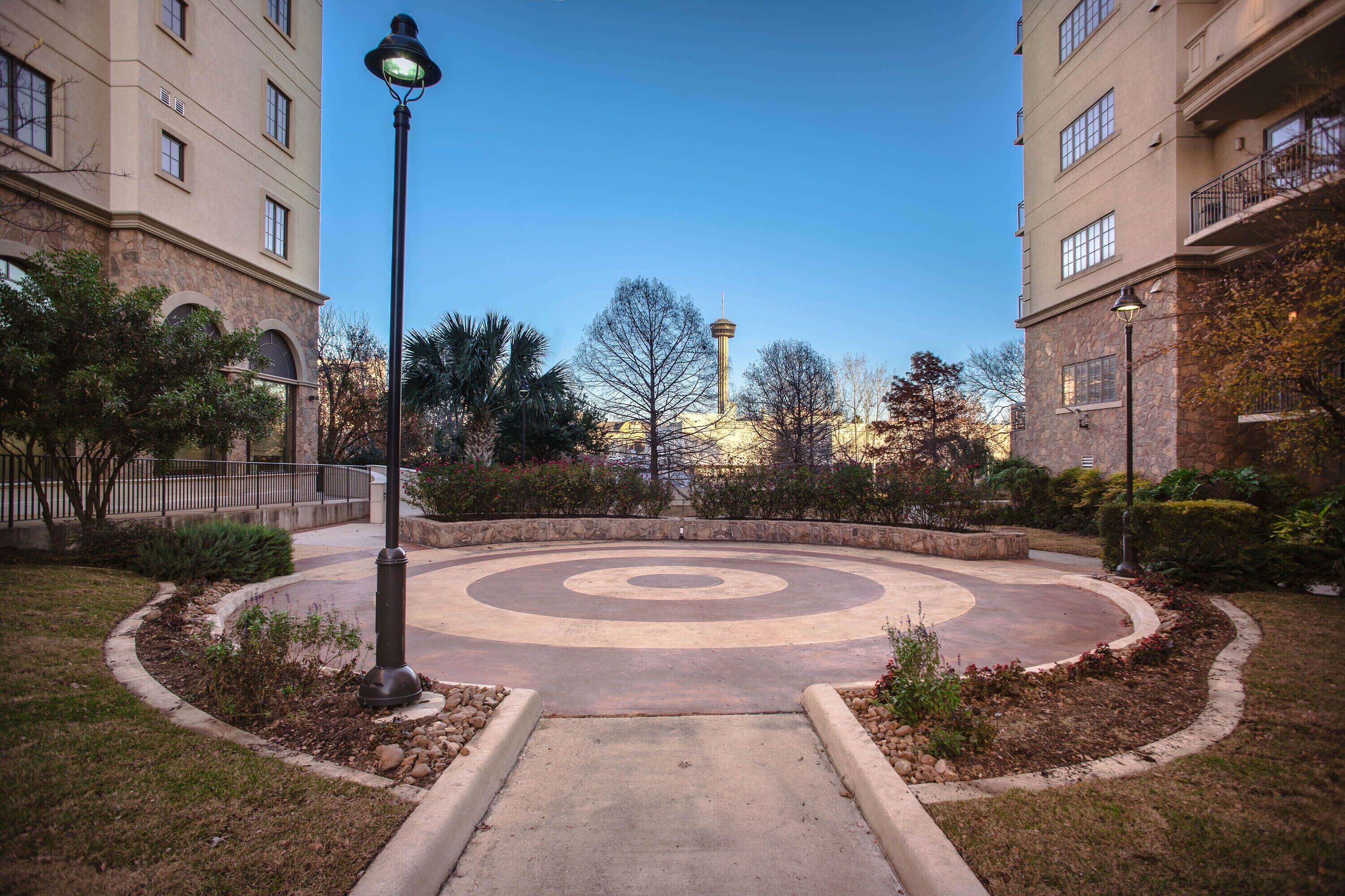 A courtyard with a circular design, a lamp post, and surrounding buildings.