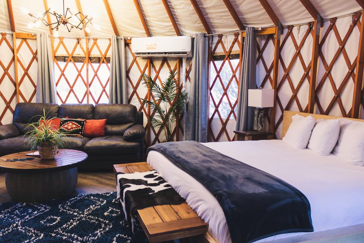 A tent with a bed, a sofa, a coffee table, and a lamp.