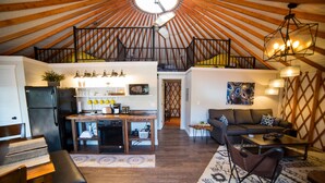 Ein geräumiges Loft mit hohen Decken, einer Küchenzeile, einem Wohnbereich mit Sofa und Couchtisch sowie einer Treppe zu einer erhöhten Ebene.