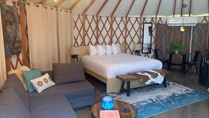 Ein gemütliches Zimmer mit Bett, einer Couch, einem Couchtisch und einer Essecke mit Stühlen.