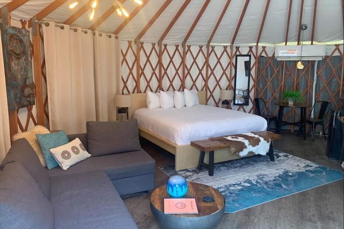 A cozy room with a bed, a sofa, a coffee table, and a dining area with chairs.