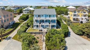 A multi-story residential building with a balcony, surrounded by lush greenery and other houses. - Oceanfront duplex with direct beach access (Emerald Isle)