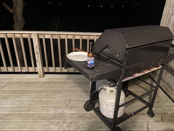 A barbecue grill on a wooden deck with a gas tank and a bottle of beer on a small table. - Sip, Splash, and Relax at Falls View Cottage! Family, Wine tours, Girls Trip! (Lodi)