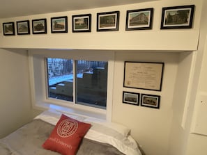 Un dormitorio con una cama, una ventana y cuadros en la pared.