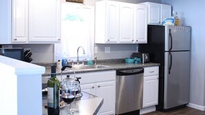 A modern kitchen with white cabinets, stainless steel appliances, and a granite countertop.