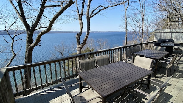 A deck with outdoor seating and a grill overlooking a body of water.