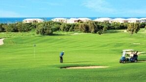 En golfbana med en puttinggreen, sandbunkrar och en golfbil.