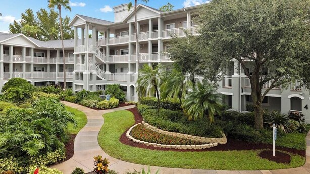 A multi-story hotel with a central courtyard, balconies, and lush landscaping.