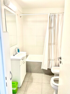 Een bad/douchecombinatie, een bidet, handdoeken