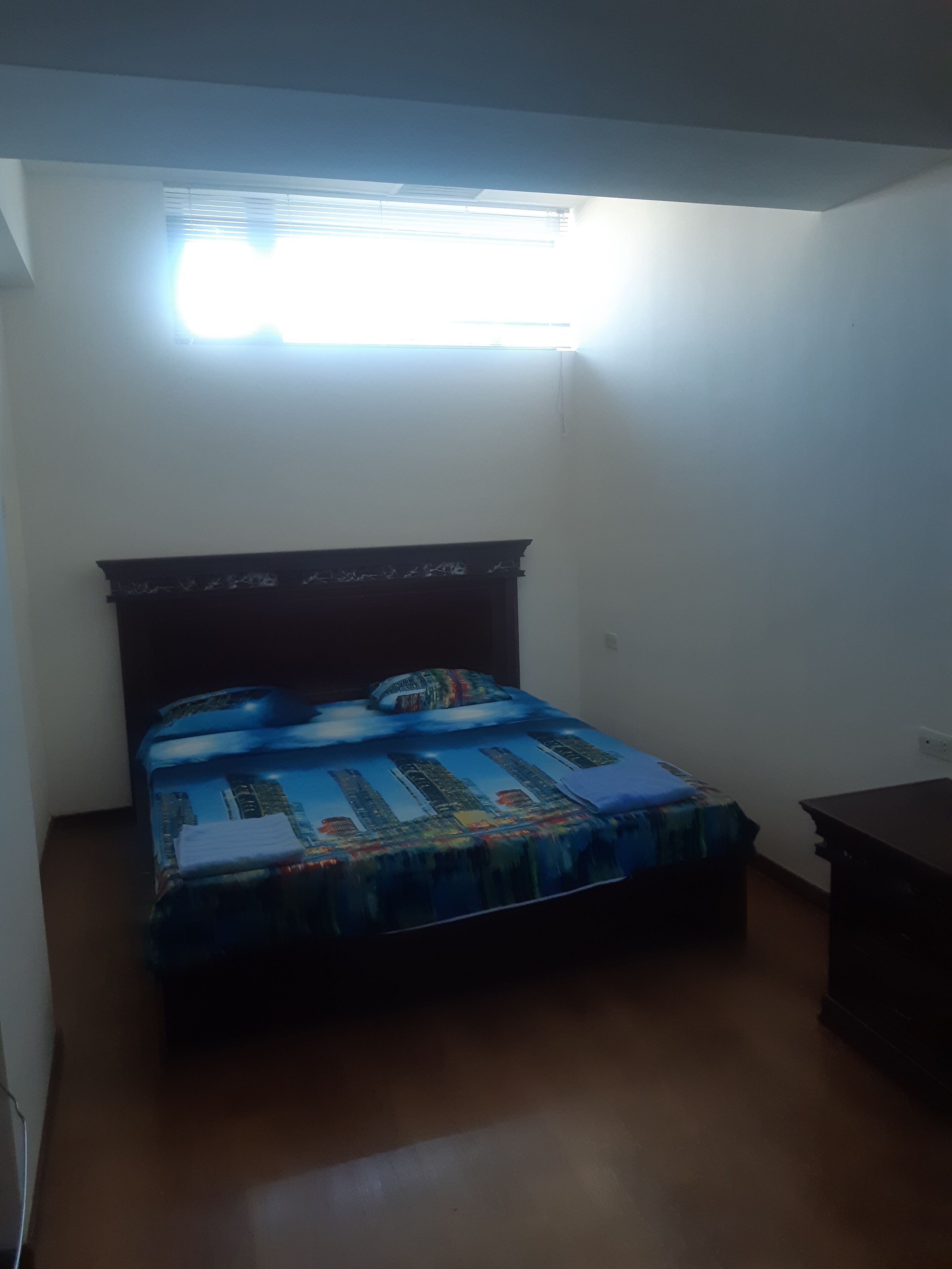 Een slaapkamer met een bed, een raam en een klein tafeltje.