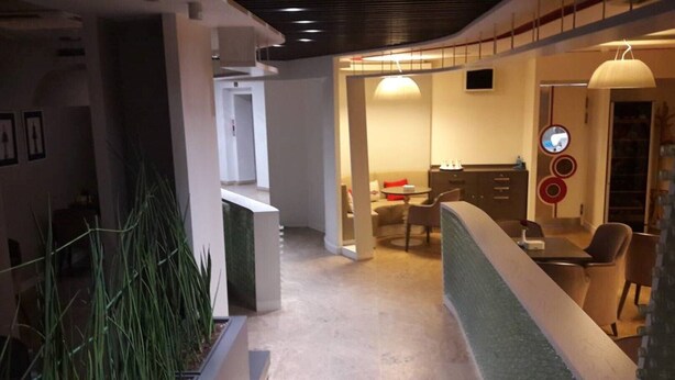 Een moderne hotelgang met een receptie, een eetruimte en een keuken, zichtbaar door een geopende deur.