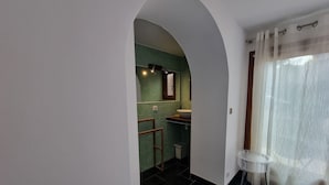 Un baño moderno con una pared de azulejos verdes, un lavabo blanco y una mesita redonda pequeña.