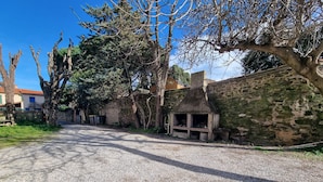 Un camino de grava que lleva a un edificio rústico con un muro de piedra y una chimenea.