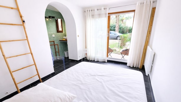 Una habitación con cama, una escalera, una mesita y vistas al exterior.