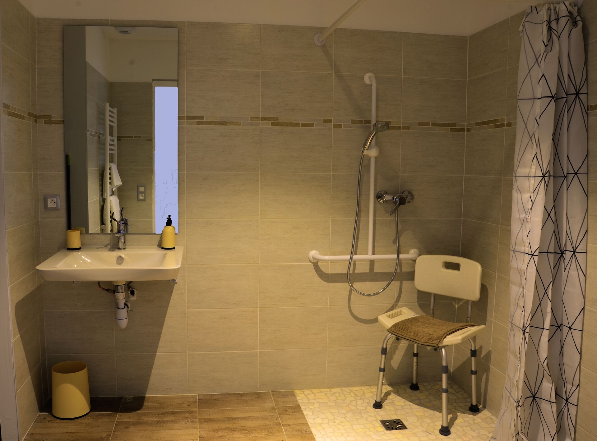 A modern bathroom with a sink, mirror, shower, and a wheelchair-accessible bench.