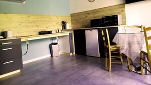 A compact kitchen with a wooden countertop, a microwave, a refrigerator, and a dining area with a table and chairs. - New residence, Le Manaka, Turquoise, calm and rest (Lamalou-les-Bains)