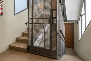 A staircase with a metal gate, a fire extinguisher, and a door at the bottom.