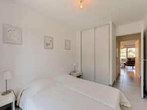 A bedroom with a bed, bedside table, lamp, and a wardrobe. There are framed pictures on the wall.