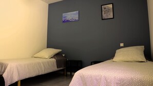Ein Zimmer mit zwei Einzelbetten, einem kleinen Tisch und zwei Bildern an der Wand.