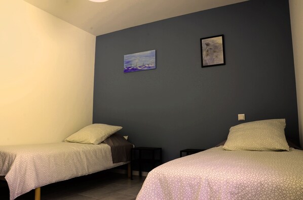 A room with two single beds, a small table, and two wall-mounted paintings. - New Residence, The Manaka, The Sapphire, calm and rest (lamalou les bains)