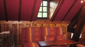Une pièce rustique avec un banc en bois, une petite table et une fenêtre donnant sur un paysage verdoyant.