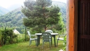 Une porte en bois donnant sur un espace verdoyant, une table avec des chaises et un pin.