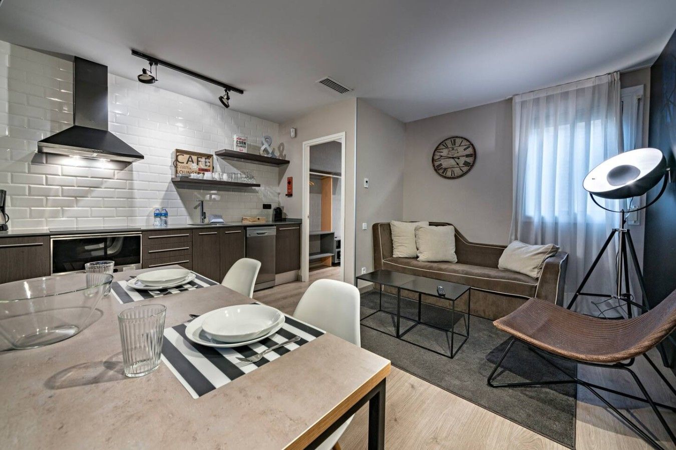 Una cocina moderna con comedor, sofá y un reloj en la pared.