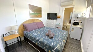 A bedroom with a bed, a TV, a desk, and a kitchenette. - Getaway Villas Unit 38-9 - comfort on a budget (EXMOUTH)