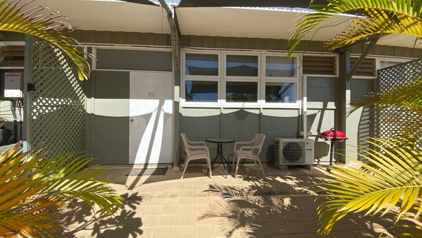 A covered patio area with a table and chairs, an air conditioning unit, and a red grill. - Getaway Villas Unit 38-9 - comfort on a budget (EXMOUTH)