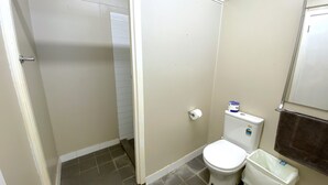 A small, compact bathroom with a toilet, a trash bin, and a towel hanging on a rack. - Getaway Villas Unit 38-9 - comfort on a budget (EXMOUTH)