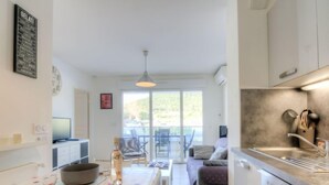 A modern kitchen with a dining area, a large window, and a view of the outdoors. - Royal Rivage by Interhome (Carqueiranne)