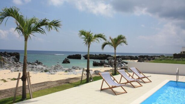 A poolside area with lounge chairs and a view of the beach and ocean. - Thalassa Beach and Pool Villa (Yoron)