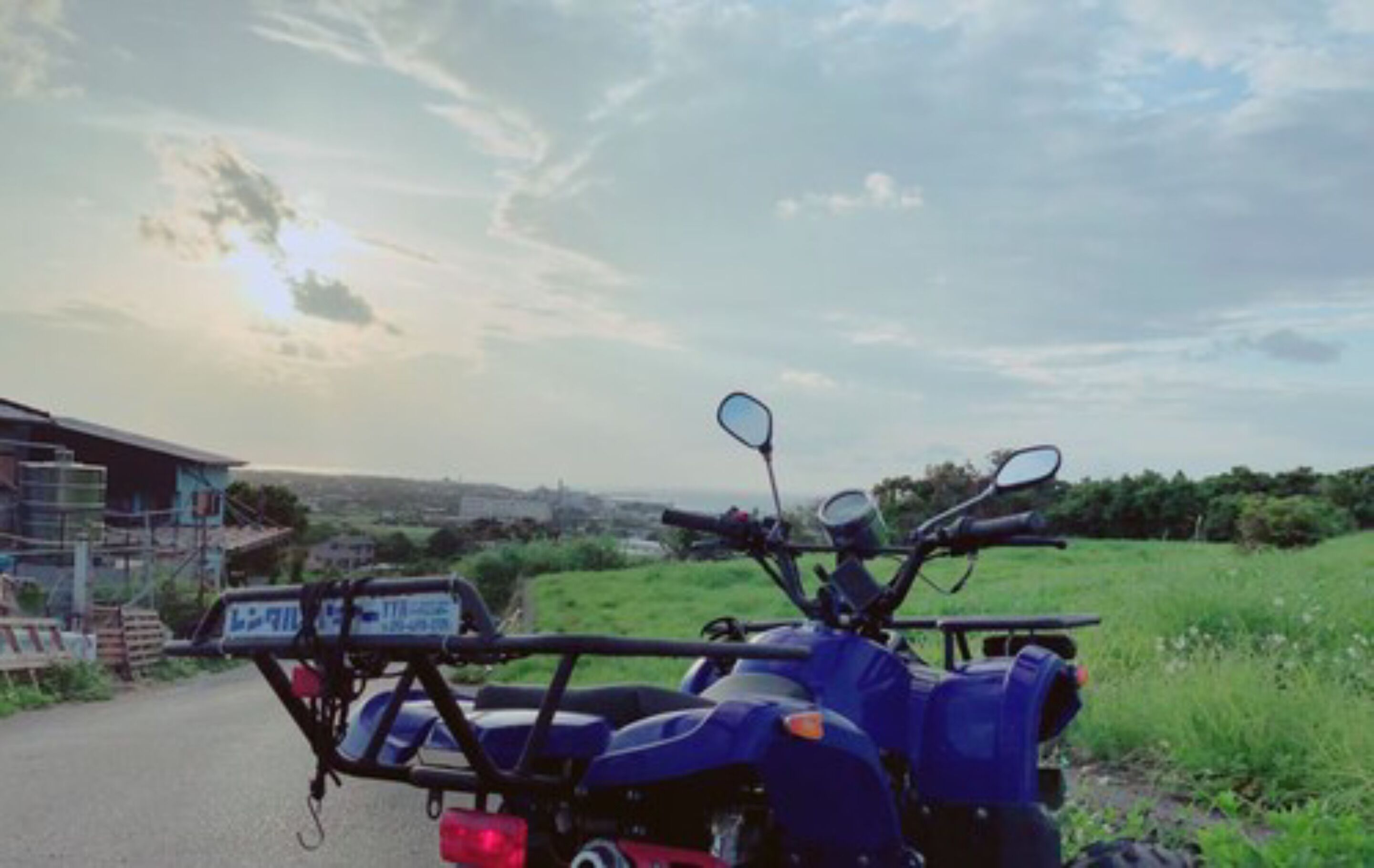 A motorcycle parked on a road with a clear sky and greenery in the background.