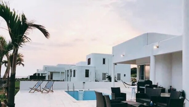 A modern outdoor area with a pool, lounge chairs, and a dining setup. - Thalassa Beach and Pool Villa (Yoron)