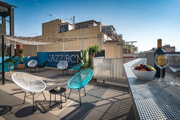 A rooftop terrace with outdoor seating, a bar area, and a view of the building labeled 'JAZZ BCN'.