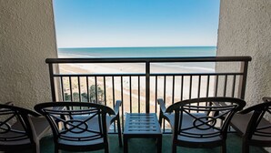 A balcony with a view of the beach, featuring a table and four chairs. - Beautiful Oceanfront, Full Kitchen, Pet Friendly (Myrtle Beach)