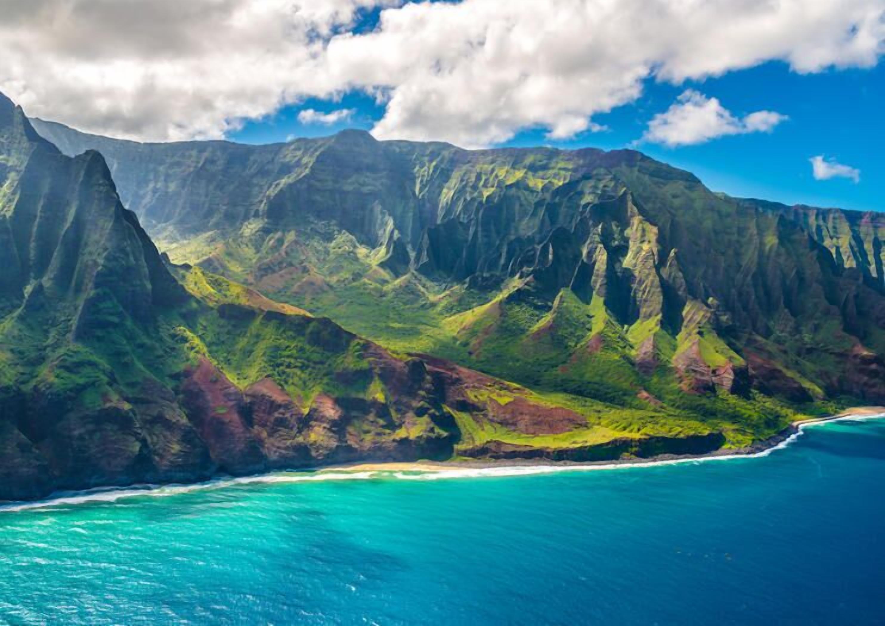 A coastal mountain landscape with a clear view of the ocean and a beach.