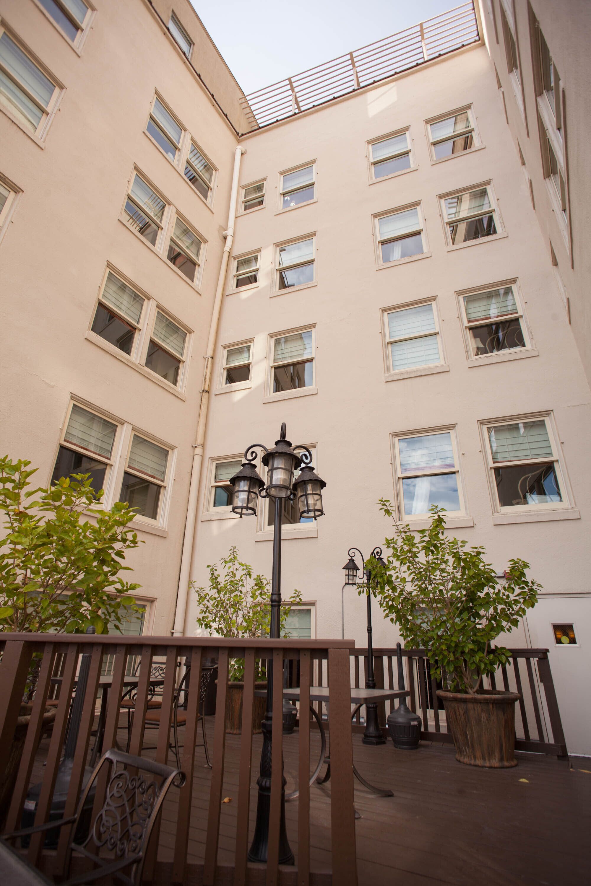 A multi-story building with a balcony, a street lamp, and potted plants.